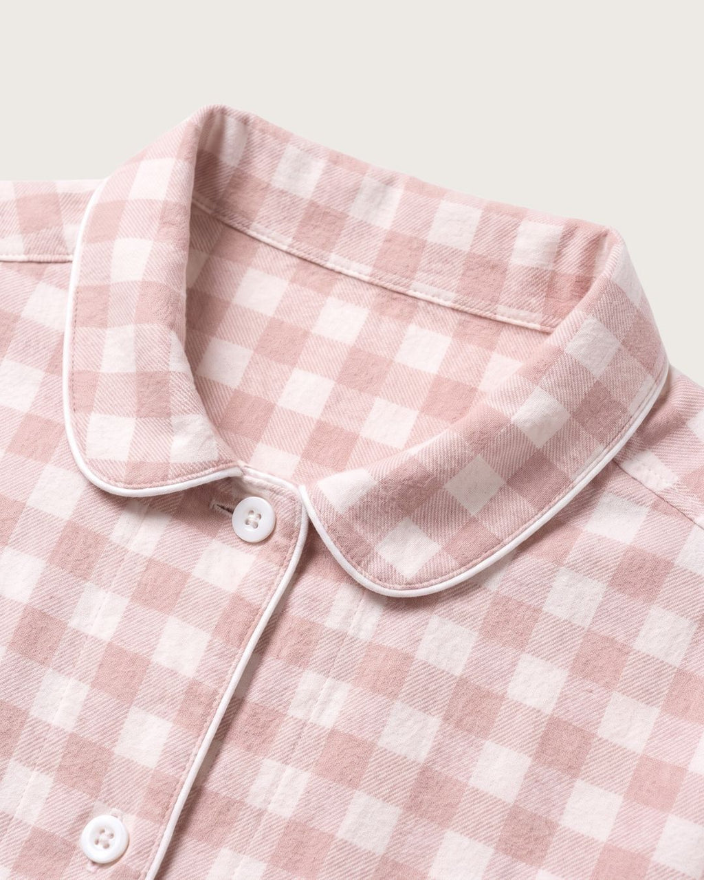 Close-up of Faye pink plaid flannel pajama collar, buttons and contrast piping