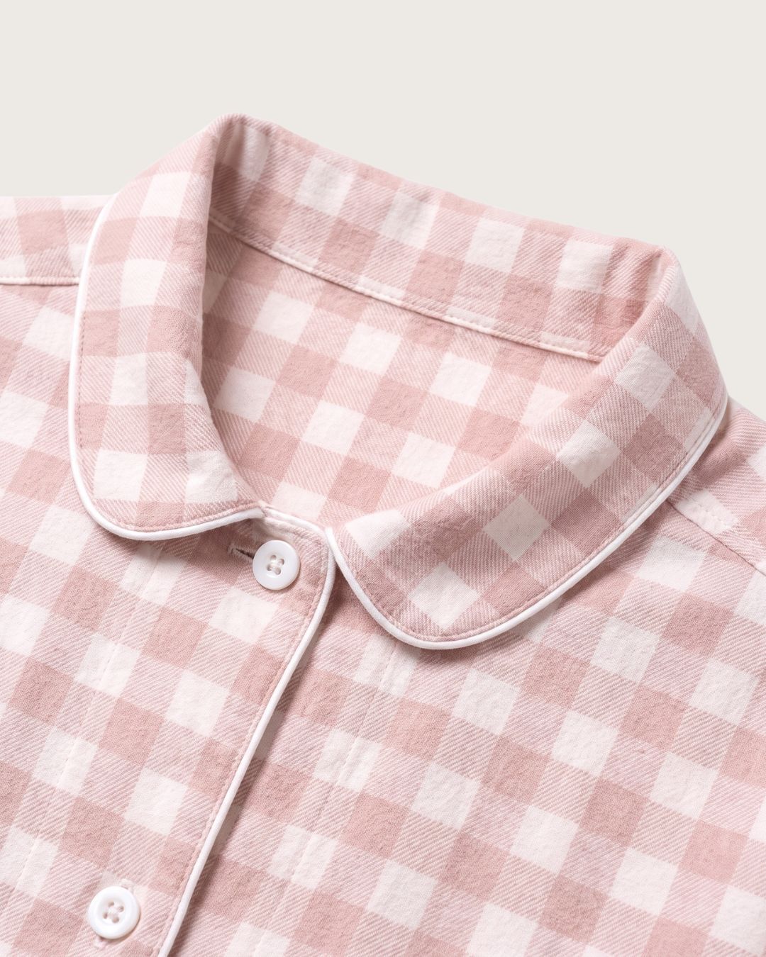 Close-up of Faye pink plaid flannel pajama collar, buttons and contrast piping