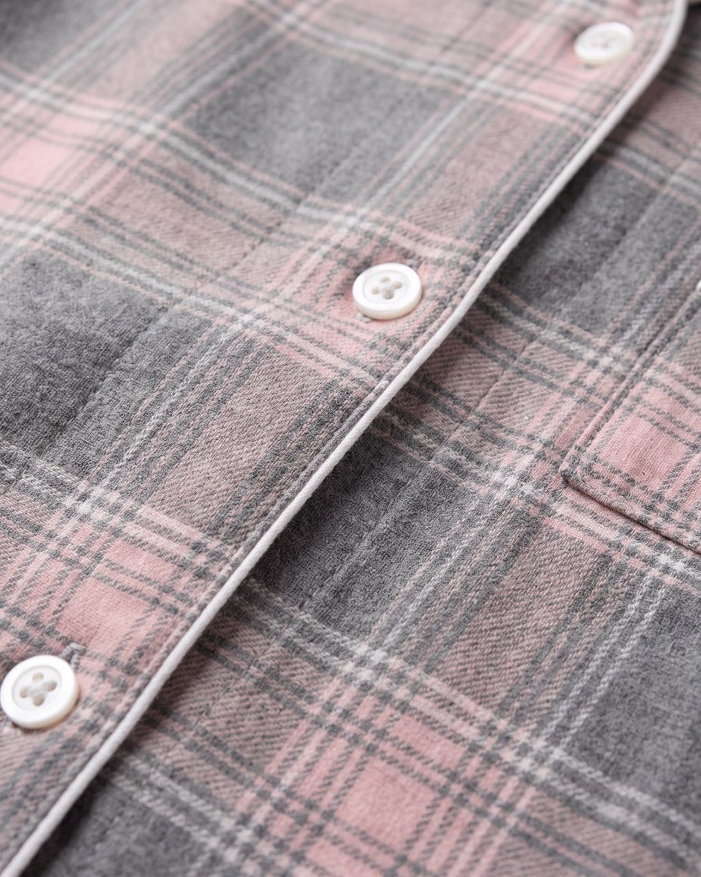 Close-up of gray plaid flannel fabric with subtle pink accents and white piping